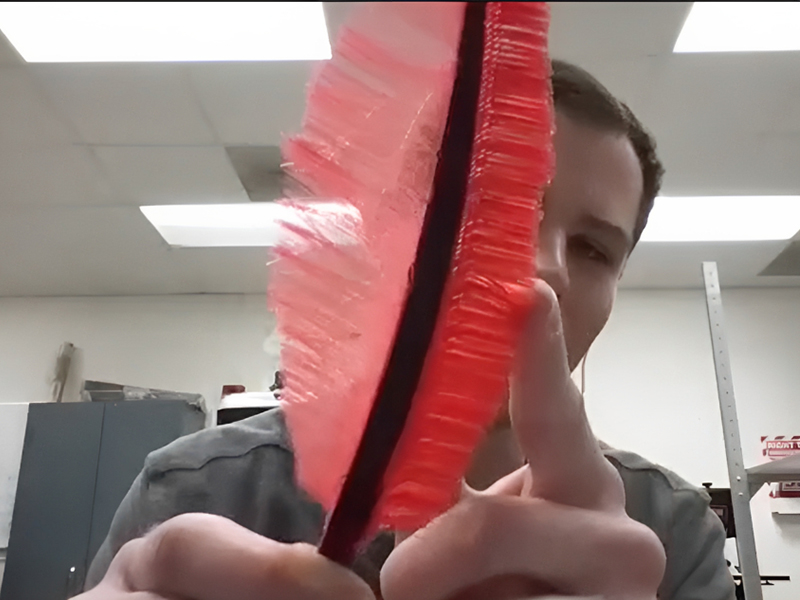Will Johnston holds up a 3D printed owl feather. 