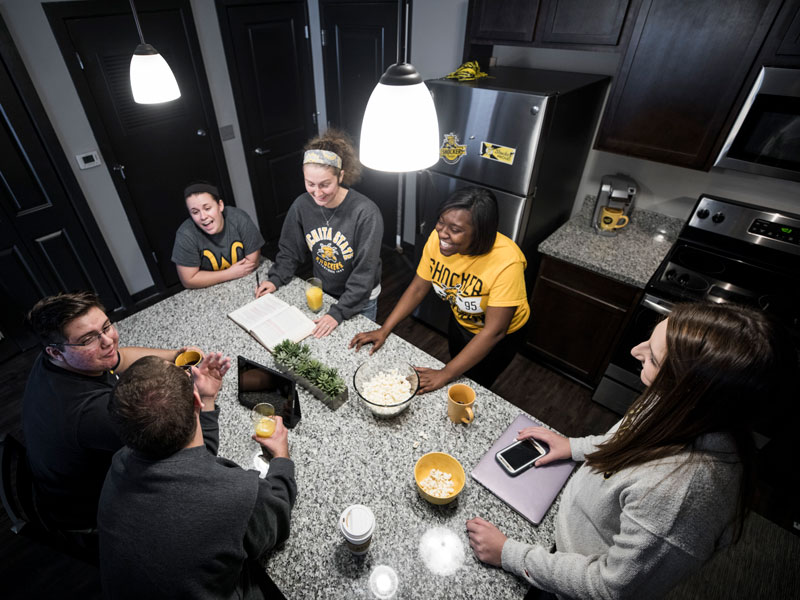 Group of students around an island in a kitchen in the Flats Apartments.